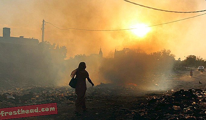 Een vrouw loopt langs een vuilnisbrand in Oost-Delhi. Volgens de Wereldgezondheidsorganisatie is de luchtvervuiling in Delhi de ergste ter wereld.